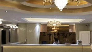 Een hotel receptie met een kroonluchter, een receptiebalie en een bord met vreemde tekens.