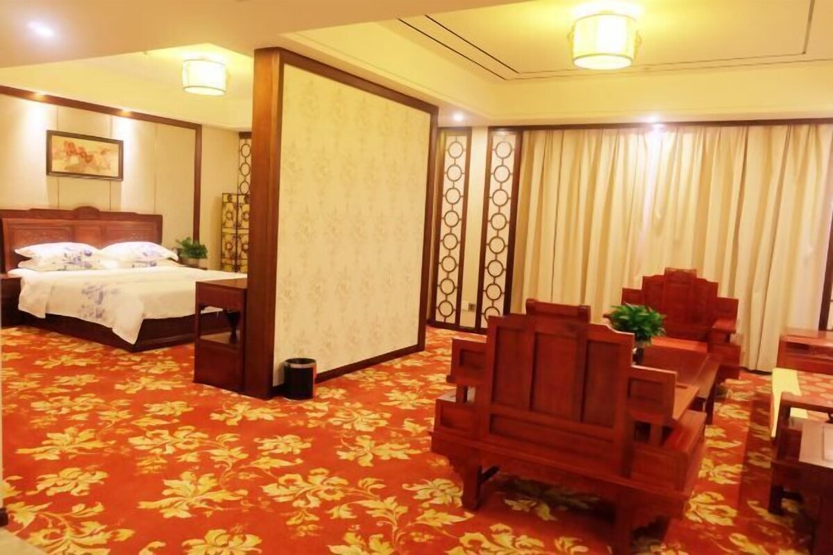 Una habitación de hotel con cama, escritorio, silla y piso alfombrado.