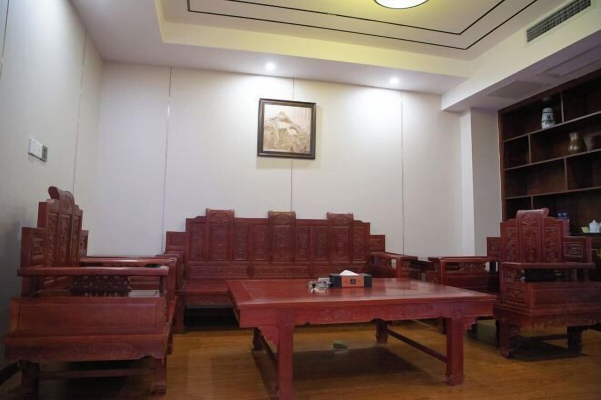 Un conjunto de comedor de madera tradicional con mesa y sillas, un cuadro enmarcado en la pared y un armario de madera con estantes.
