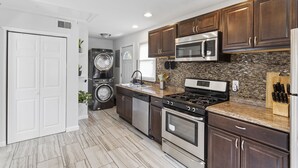 A modern kitchen with stainless steel appliances, dark wood cabinets, and a granite countertop.