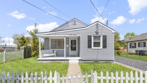 A single-story house with a porch, a small front yard, and a white picket fence.