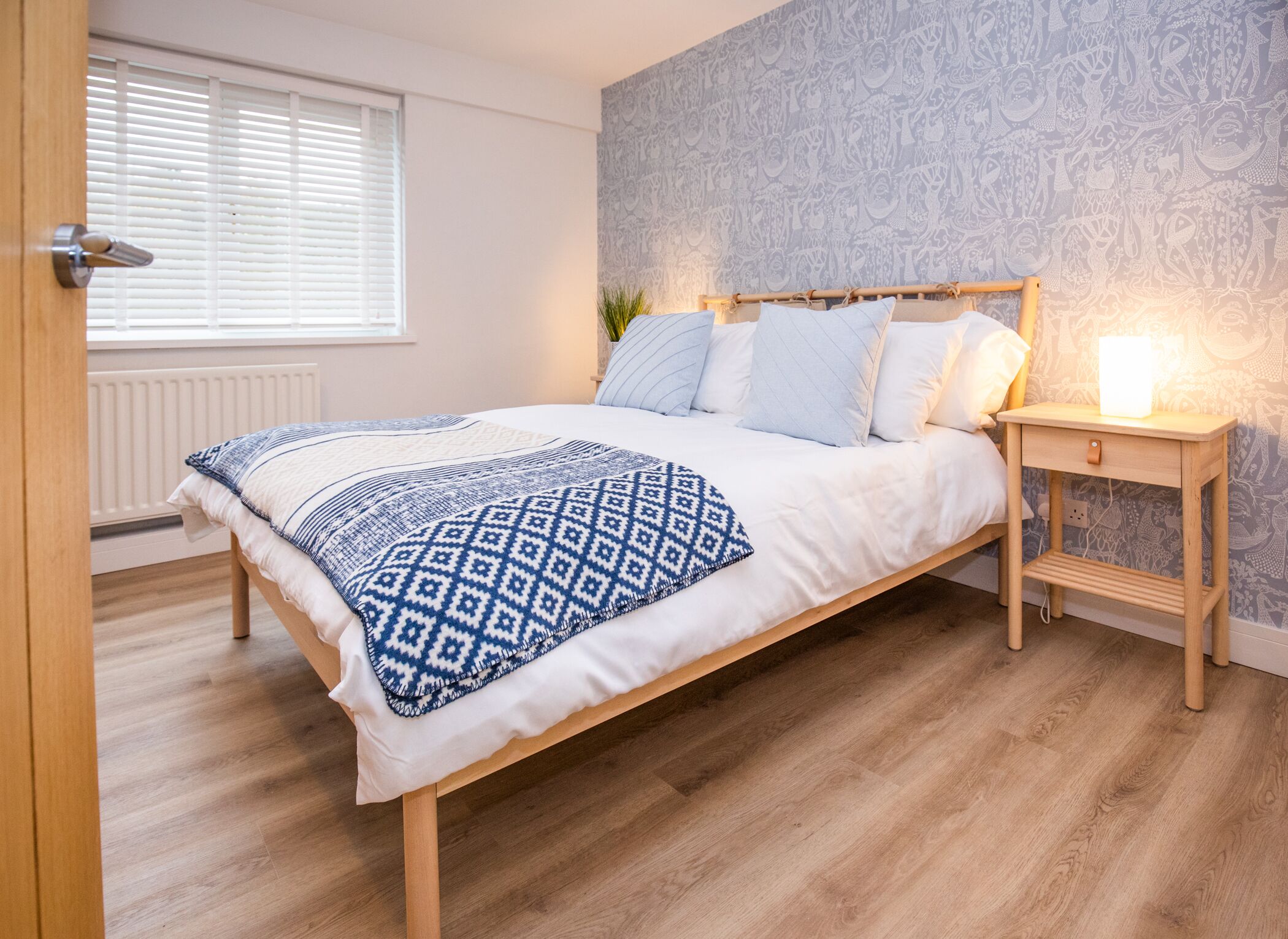 A bedroom with a bed, bedside table, and a radiator.