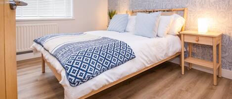 A bedroom with a bed, bedside table, and a radiator.