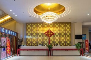 A reception area with a chandelier, a patterned wall, and a reception desk. - Suopurui International Hotel (Linying)