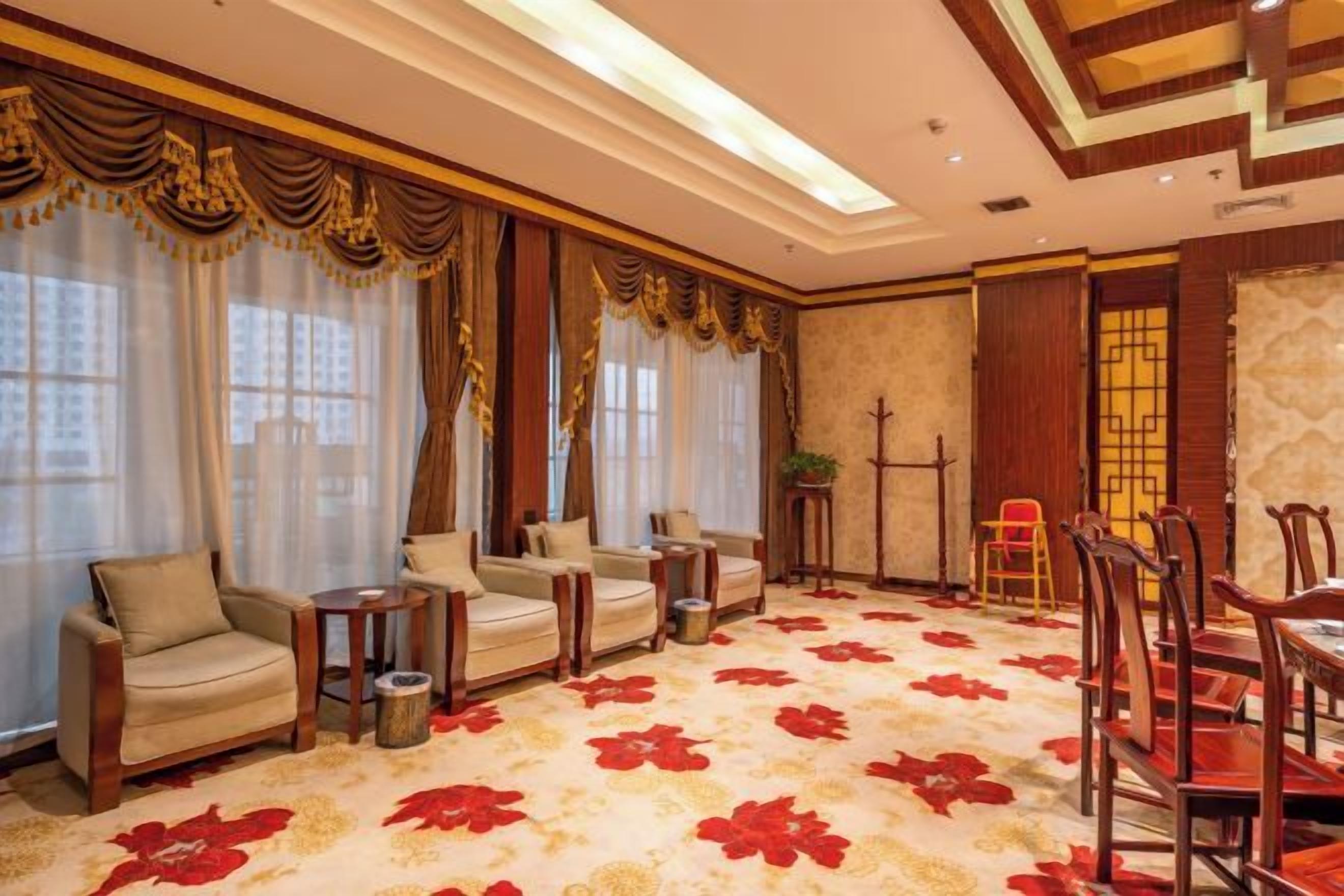 Habitació d'hotel amb una gran catifes floral, diverses zones d'estar i una taula de menjador.