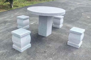 Una mesa redonda de piedra con cuatro pedestales de piedra a juego.