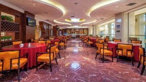 A spacious restaurant with marble flooring, orange chairs, and red tablecloths. - Suopurui International Hotel (Linying)