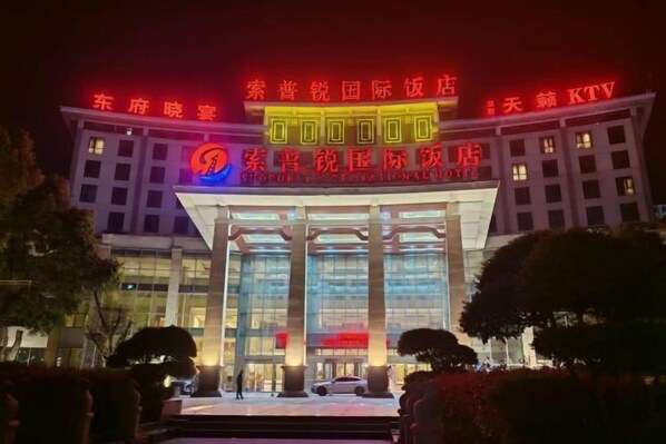 A hotel with a prominent entrance, large columns, and illuminated signage. - Suopurui International Hotel (Linying)