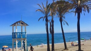 Une plage avec une tour de surveillance, des palmiers et des gens qui prennent un bain de soleil.