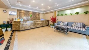 A hotel reception area with a marble reception desk, a blue sofa with patterned cushions, and a coffee table. - Jinjiang Inn Fashion Chongqing Jiangbei Liyuchi Changan Automobile (Chongqing)