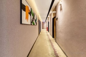 A long, narrow hotel corridor with framed artwork on the walls, a carpeted floor, and doors on the right side. - Moli Hotel (Guangzhou Yongqingfang Zhongshan 8th Road Subway Station) (Guangzhou)