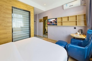 A hotel room with a bed, a TV, a small table, and a blue chair. - Moli Hotel (Guangzhou Yongqingfang Zhongshan 8th Road Subway Station) (Guangzhou)