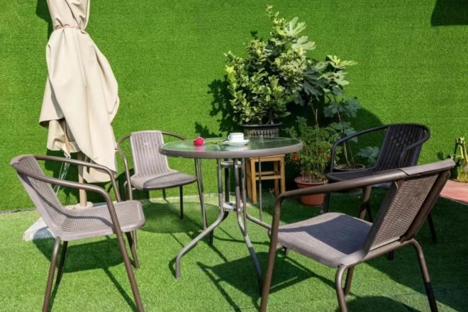 Un área de estar al aire libre con una mesa redonda, cuatro sillas y una planta en maceta.