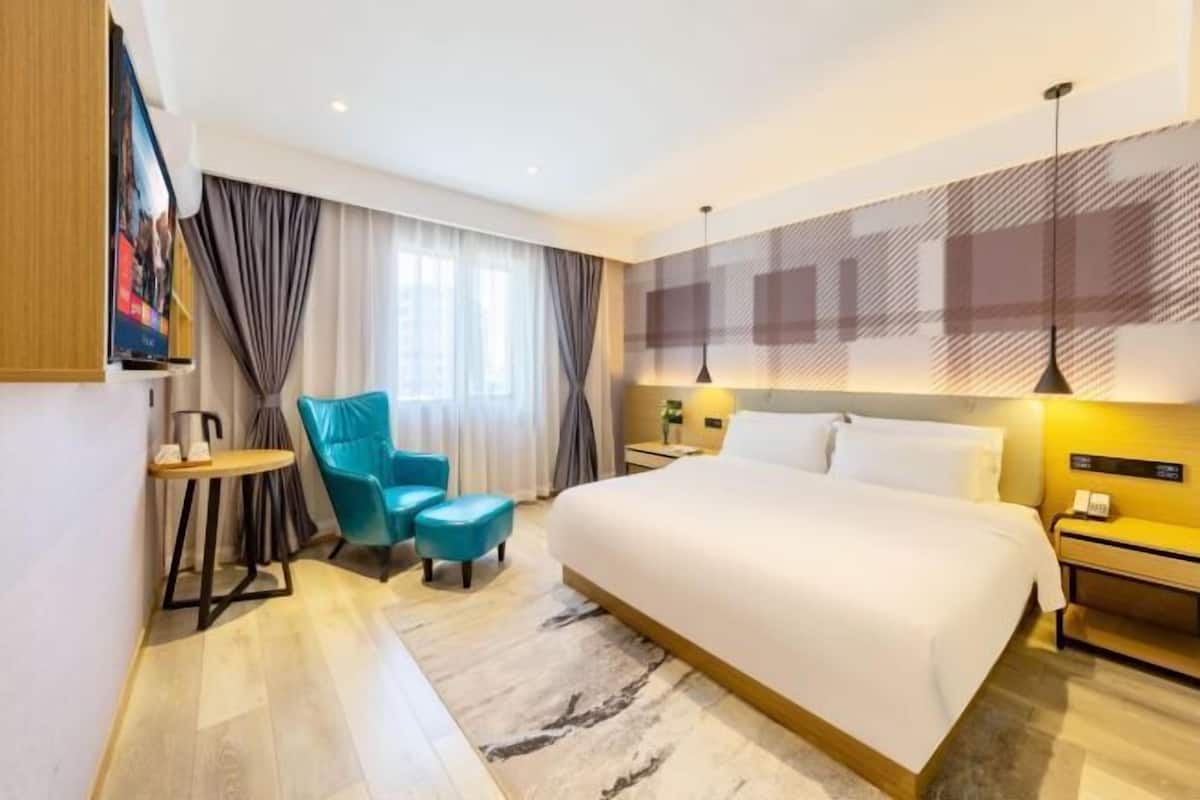 Una habitación de hotel moderna con una cama grande, un escritorio pequeño, una silla y un televisor.