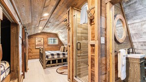 A rustic wooden room with a bed, a glass shower, and a wooden cabinet. - Farmhouse Cabin Rustic Ridge: Hot Tub & Pets! (Blue Ridge)