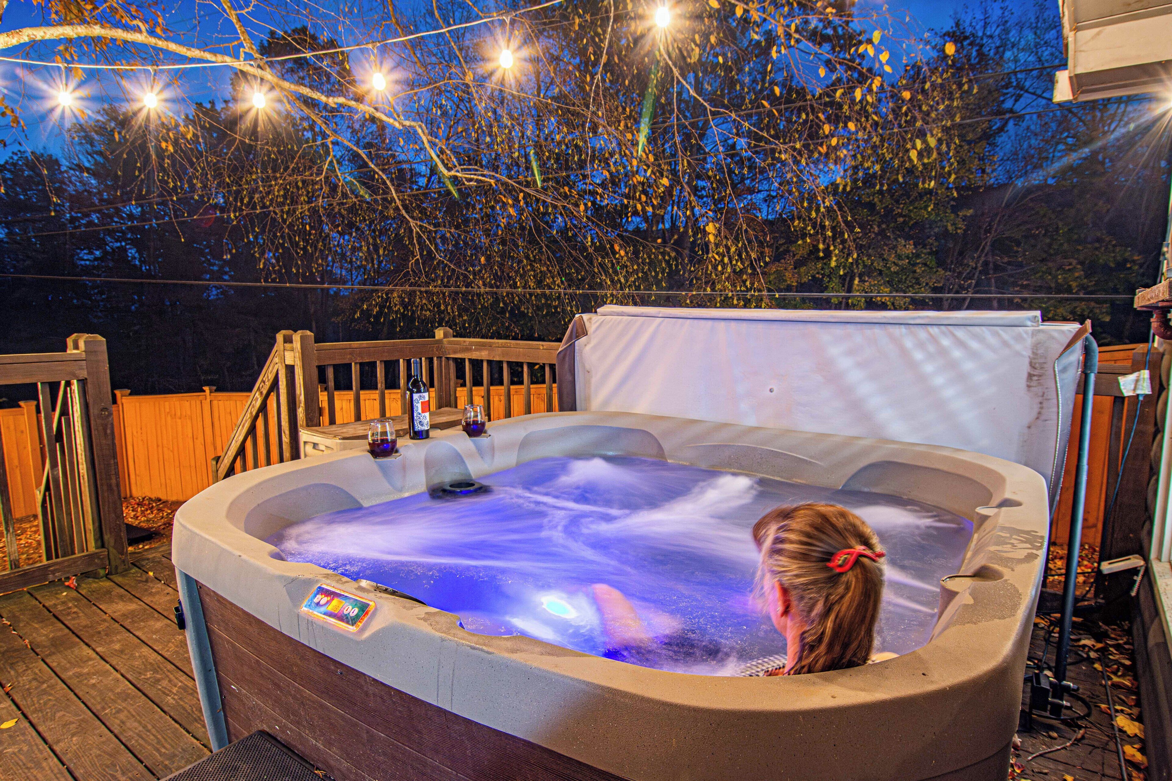 A hot tub on a wooden deck with a wooden railing and a wooden fence in the background.