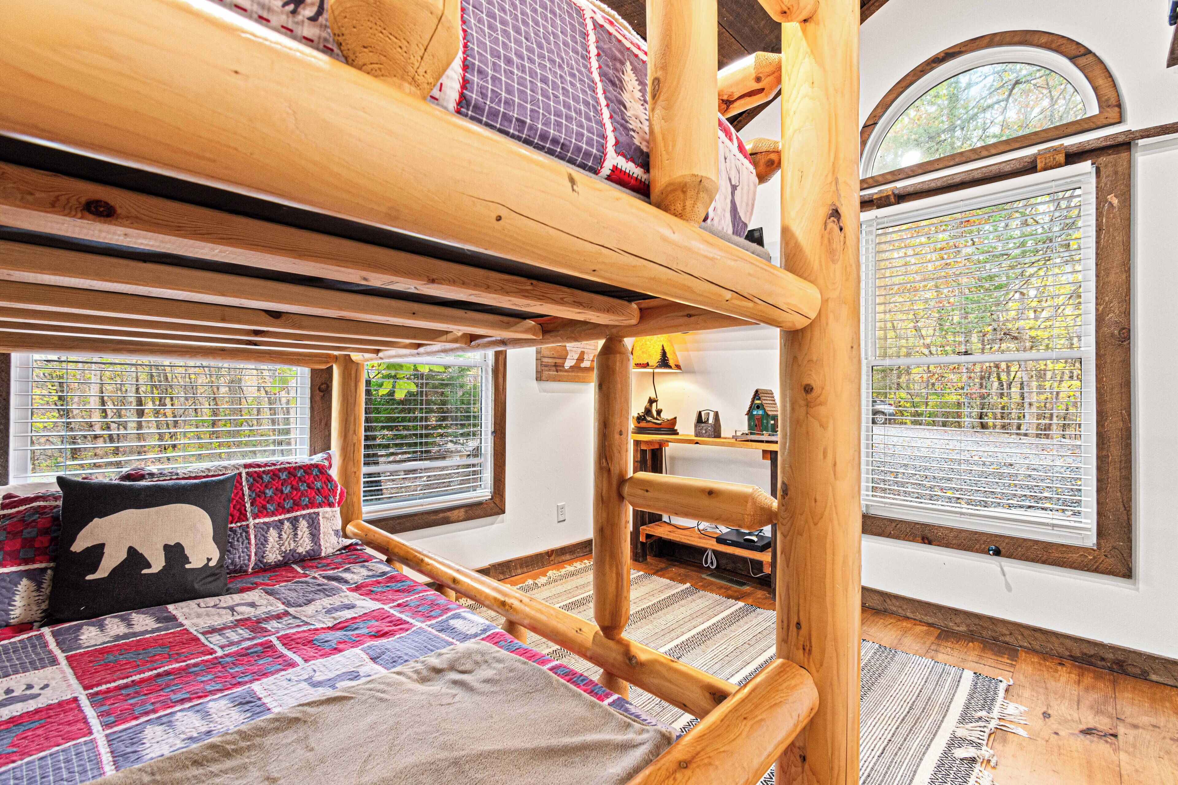 A bunk bed with a quilted bedspread, a wooden ladder, and a window with blinds.