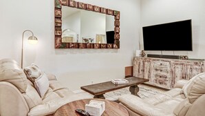 Ein Wohnzimmer mit einem großen Spiegel, einem Flachbildfernseher, einem Couchtisch und einem Sofa.