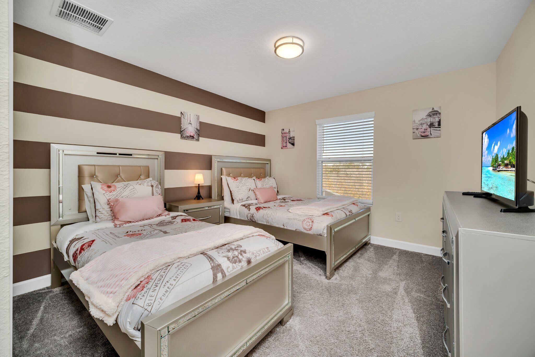 A bedroom with two beds, a TV, and a dresser.