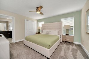 A bedroom with a large bed, a ceiling fan, a dresser, and a nightstand. - Comfy, Spacious, Newly Decorated With Lovely Pool Near Disney! (Davenport)