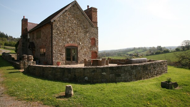 Un bâtiment en pierre avec une cheminée en briques, une porte et une fenêtre.