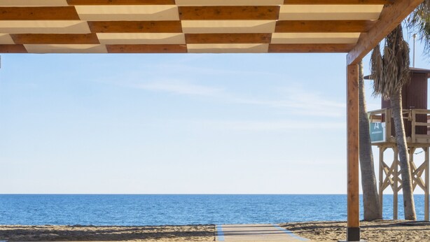 A wooden pier leading to a beach with a clear view of the ocean.