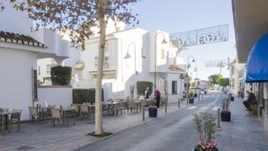 A street with outdoor seating, white buildings, and a blue awning.