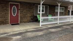 A two-story house with a red door, stone exterior, and a white picket fence. -  The Bear Cave w hot tub in the quaint village of Aurora (Hardin)