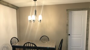 A dining room with a rectangular table, four chairs, a chandelier, and a white door. -  The Bear Cave w hot tub in the quaint village of Aurora (Hardin)