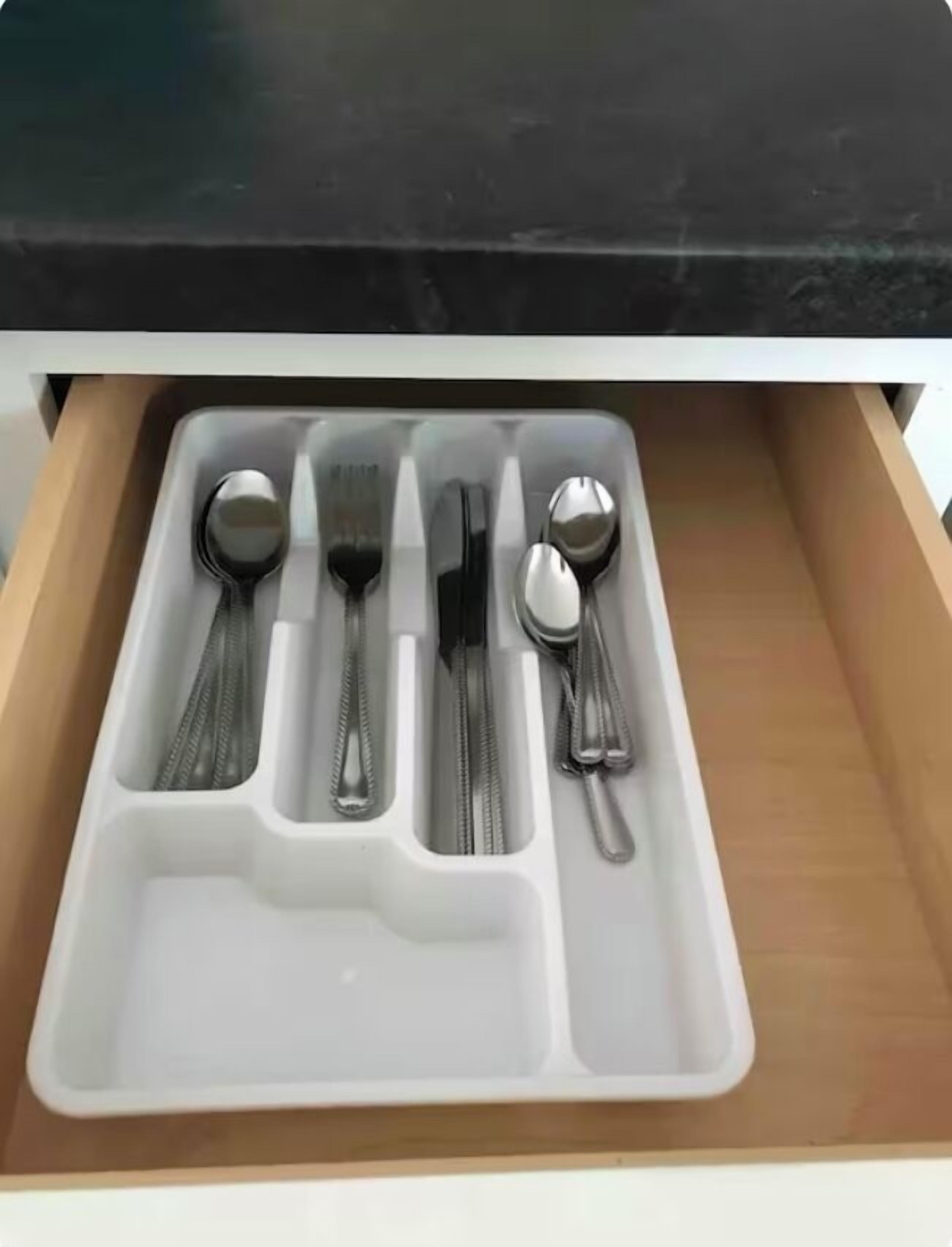 Un cajón con separadores que contiene varios utensilios como tenedores, cucharas y cuchillos.