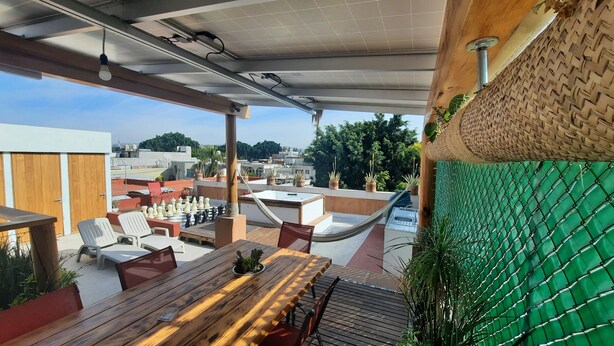 An outdoor seating area with a chessboard, wooden tables, and chairs.