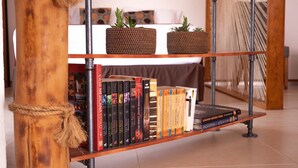 A bookshelf with books and two woven baskets on top.