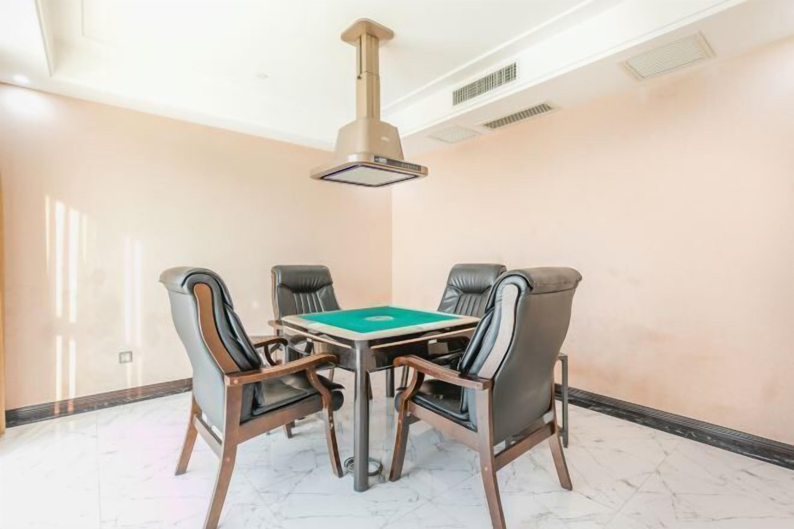Une salle de conférence équipée d’une table et de quatre chaises, d’un climatiseur fixé au plafond et d’un sol en marbre.