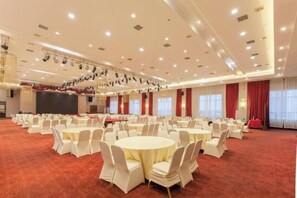 A large banquet hall with round tables and chairs, a stage, and a red carpet. - Tianzi International Hotel (Xiaogan)