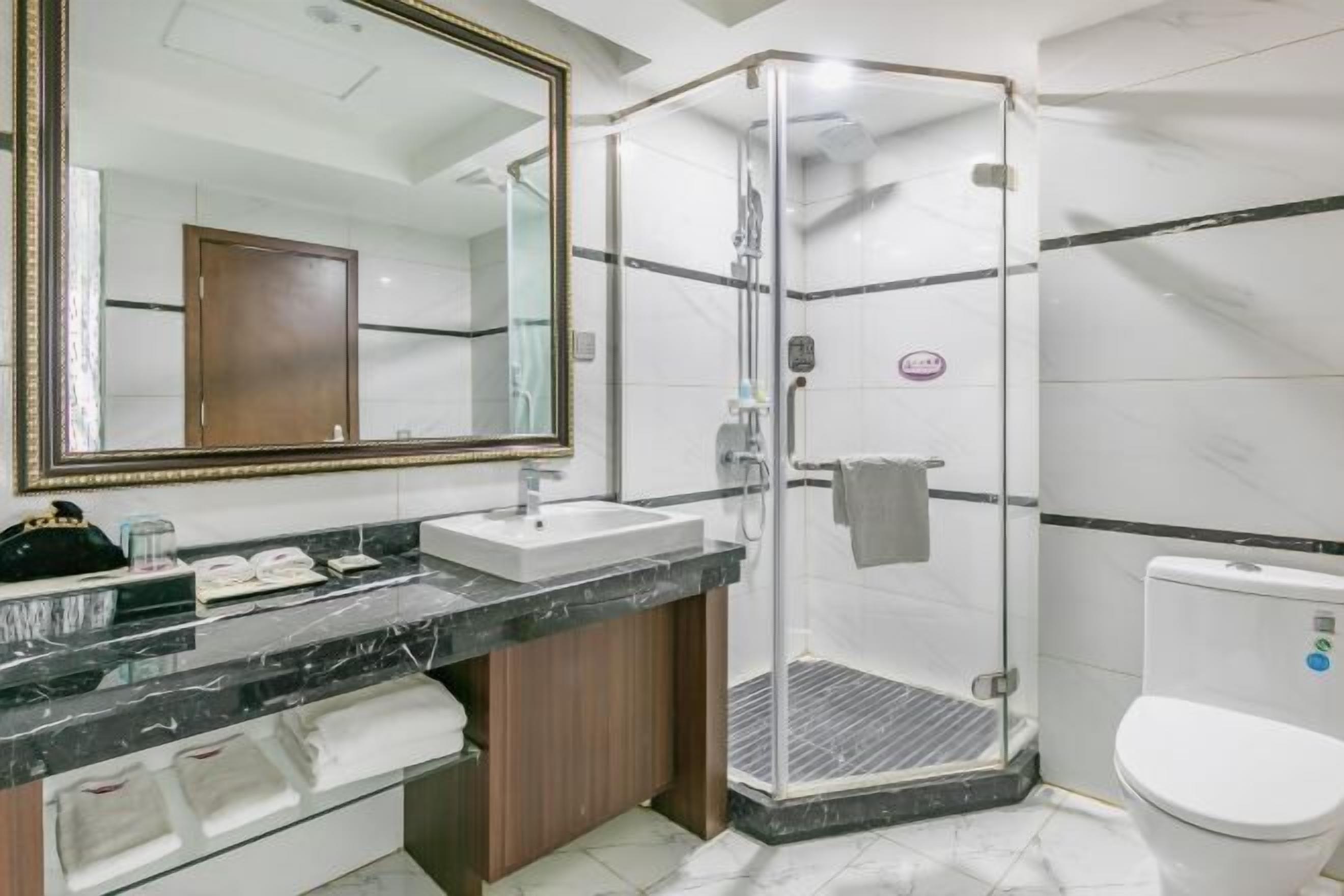 A modern bathroom with a glass-enclosed shower, a large mirror, and a white toilet.