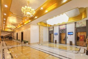 A hotel lobby with a marble floor, chandeliers, a reception desk, and a digital screen. - Tianzi International Hotel (Xiaogan)