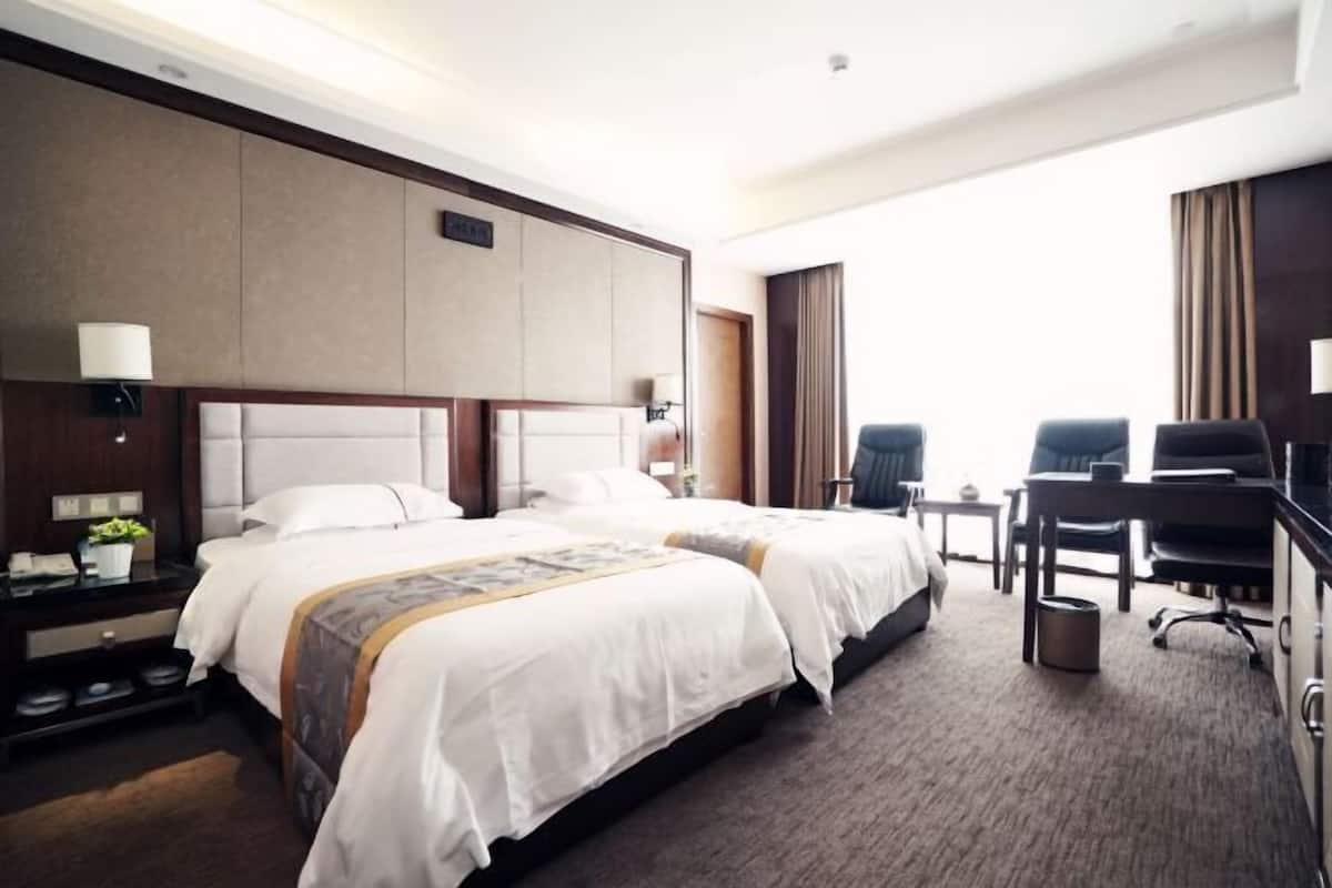 Een hotelkamer met twee bedden, een bureau, een stoel en een klein tafeltje.