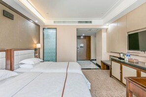 A hotel room with two beds, a television, a desk, and a bathroom visible through an open door.