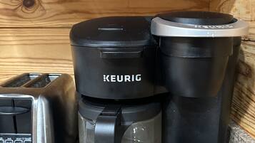 Una cafetera Keurig con jarra de vidrio y bandeja de goteo, sobre una encimera de granito junto a un tostador.