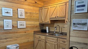 A wooden interior with a kitchen area, including cabinets, a sink, and framed pictures on the wall. - Cabin B at Smith Lake Alabama Cabins (Cullman)