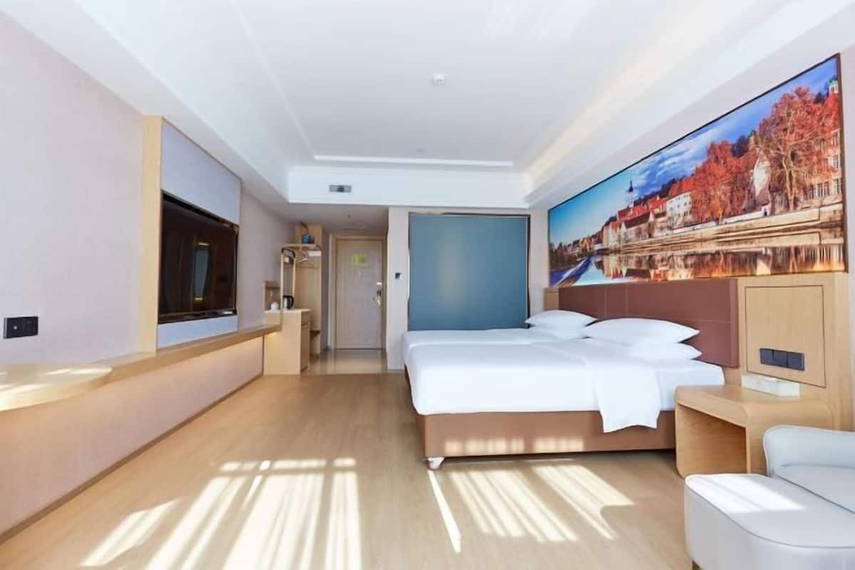 A modern hotel room with a large bed, a TV, and a painting of a cityscape.