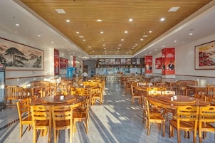 Ein geräumiges Restaurant mit Holztischen und -stühlen, einer hohen Decke mit Holzbalken und Kunstwerken an den Wänden.