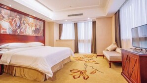 A hotel room with a large bed, a sofa, a television, and a painting on the wall. - Vienna Hotel (Yingtan International Optical City Fangte Store) (Yingtan)