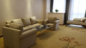 A modern living room with a beige sofa set, a glass coffee table, and a carpet with floral patterns. - Vienna Hotel (Yingtan International Optical City Fangte Store) (Yingtan)