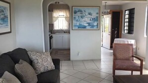 A living room with a sofa, a chair, a dining table, a kitchen area, and a painting on the wall. - Misty's Point of View (St Thomas)