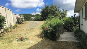 A narrow pathway leading to a house with a satellite dish, surrounded by greenery and a clear sky. - Misty's Point of View (St Thomas)