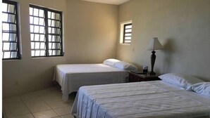 A room with two beds, a small table with a lamp, and a window. - Misty's Point of View (St Thomas)