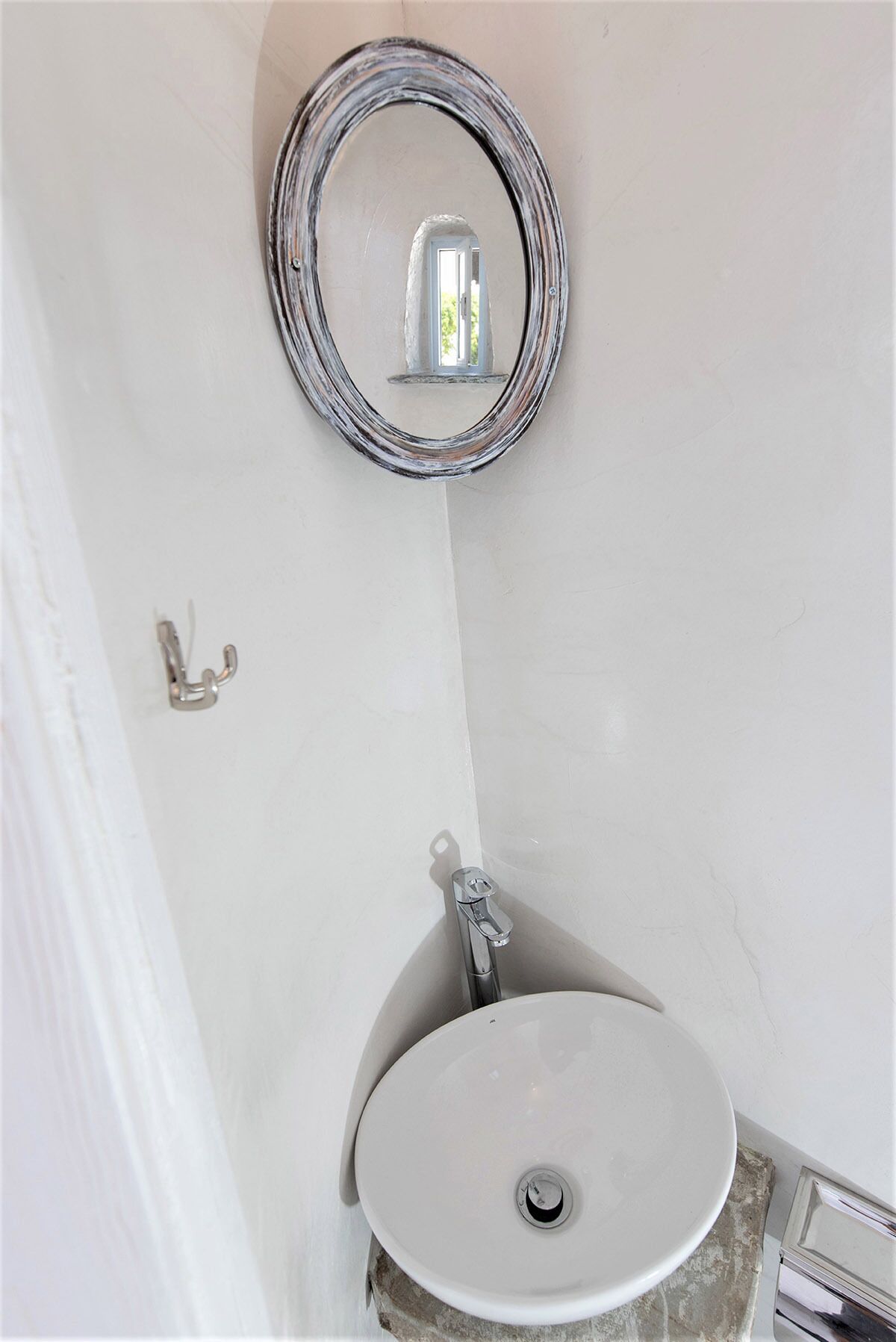 A bathroom with a white sink, a mirror with a rustic frame, and a metal faucet.