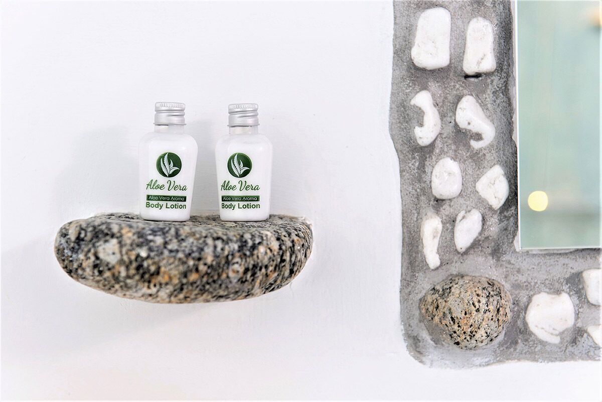 Due flaconi di lozione corpo all'aloe vera su un ripiano in pietra con venature.