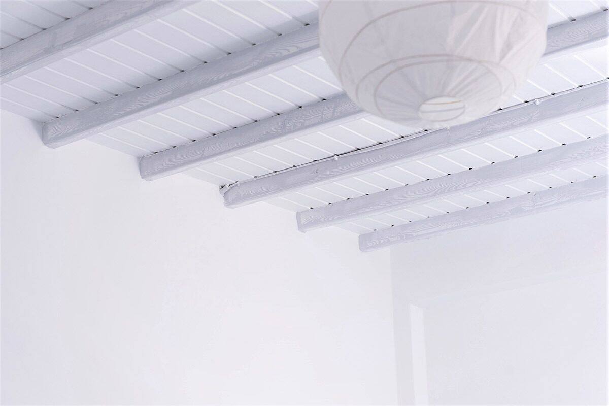 A white ceiling with wooden beams and a hanging light fixture.